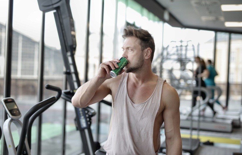 a man drinking energy drink at the gym in the morning