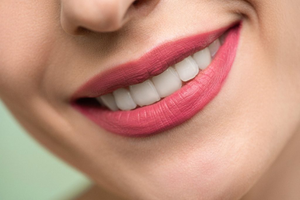 : A woman wearing pink lipstick is smiling