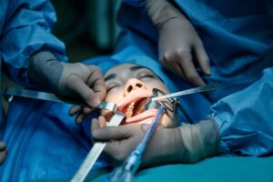 A patient is being treated for dental problems under the supervision of two skilled dentists as it involves sedation.