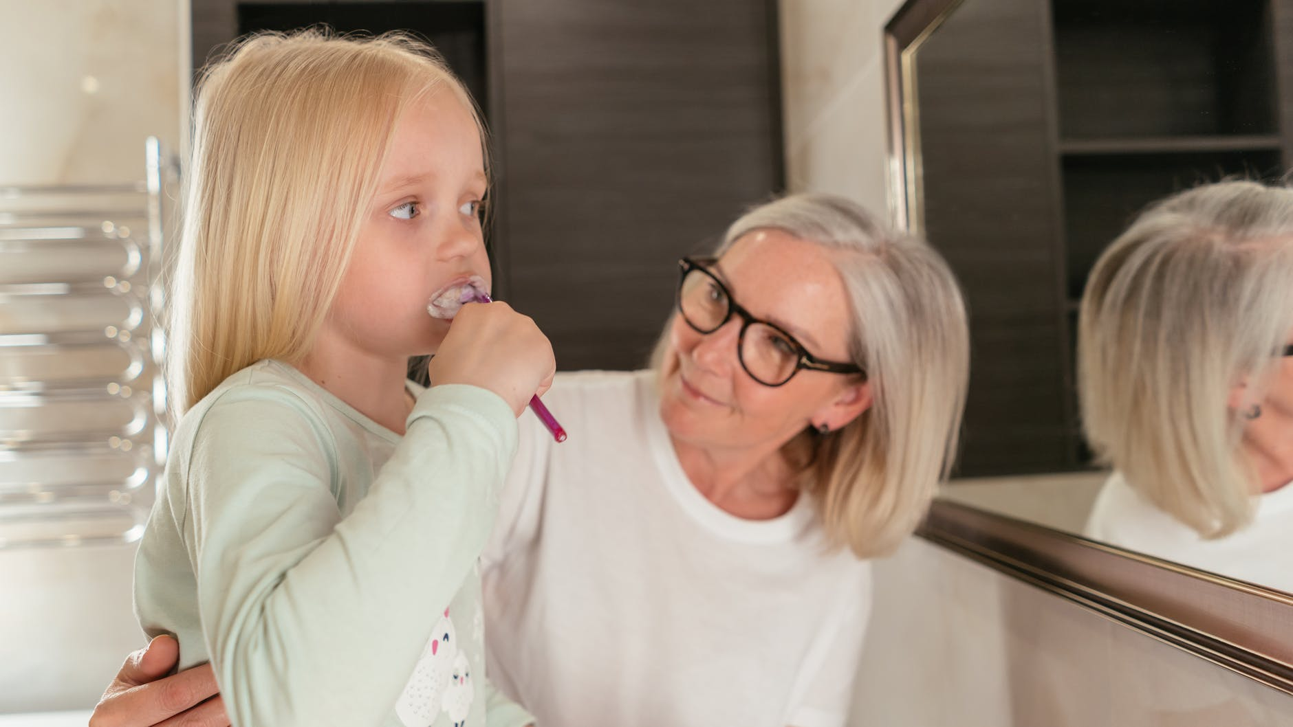 A woman teaching her daughter how to brush her teeth
