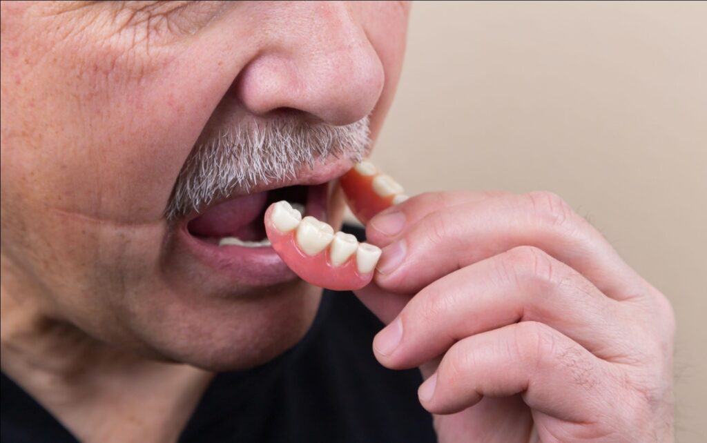 an older man is putting dentures in his mouth