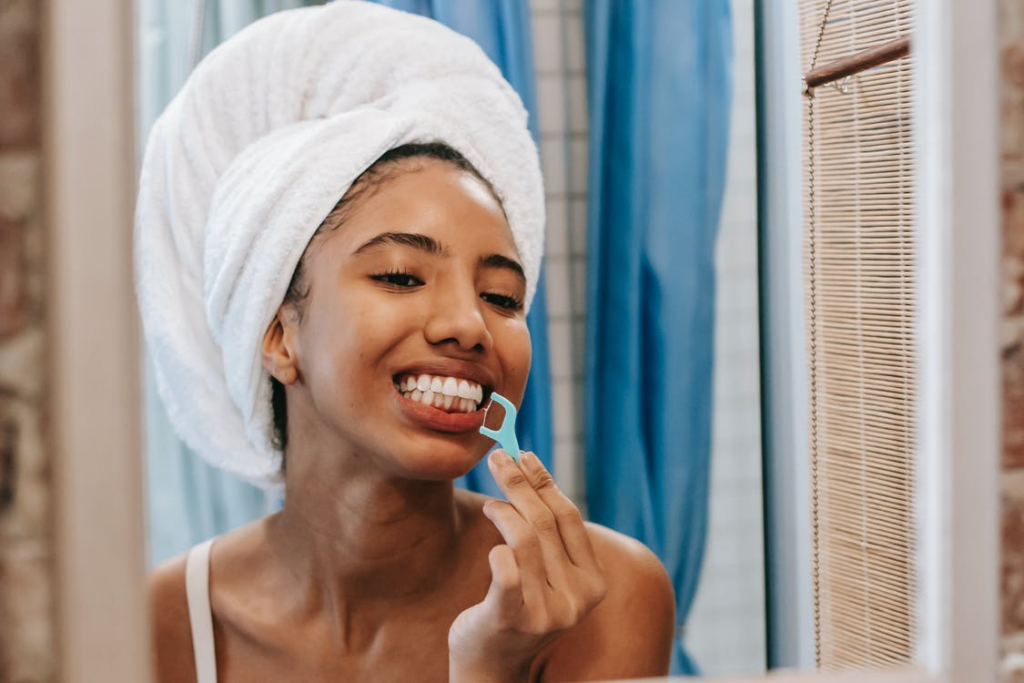 A woman is flossing her teeth.