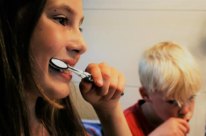 A girl and a boy brushing their teeth.