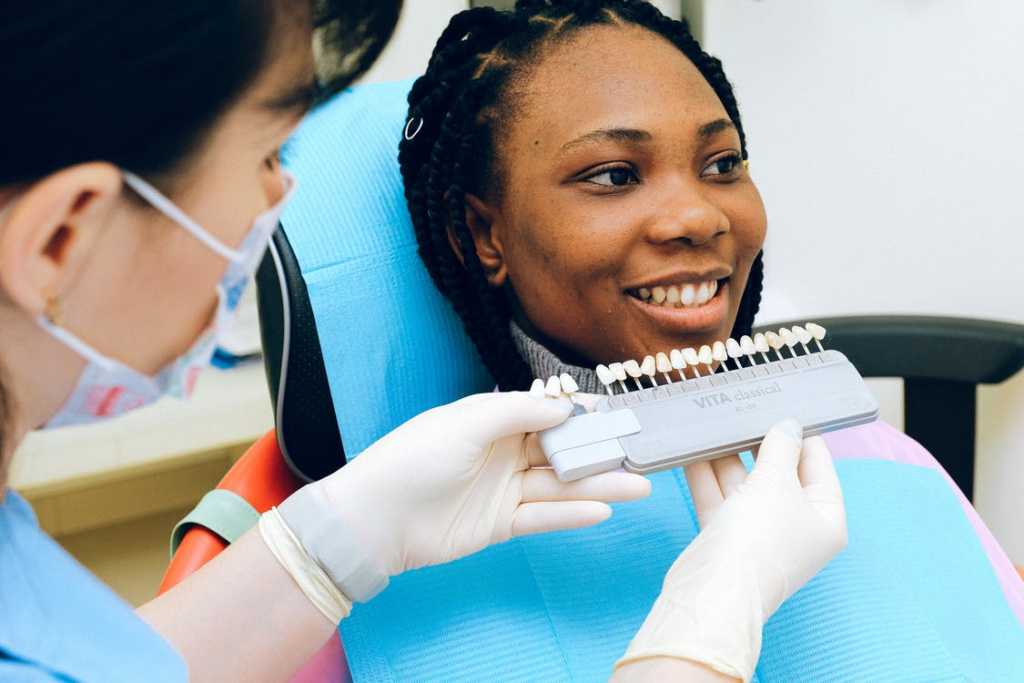 A dentist matching teeth color of the patient for dental implant