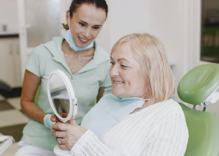 A dental hygienist helps patients put on and examine dentures