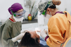 Two dentists performing a procedure on a patient’s mouth