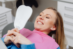 A woman smiling to check her teeth while in a dentist’s chair