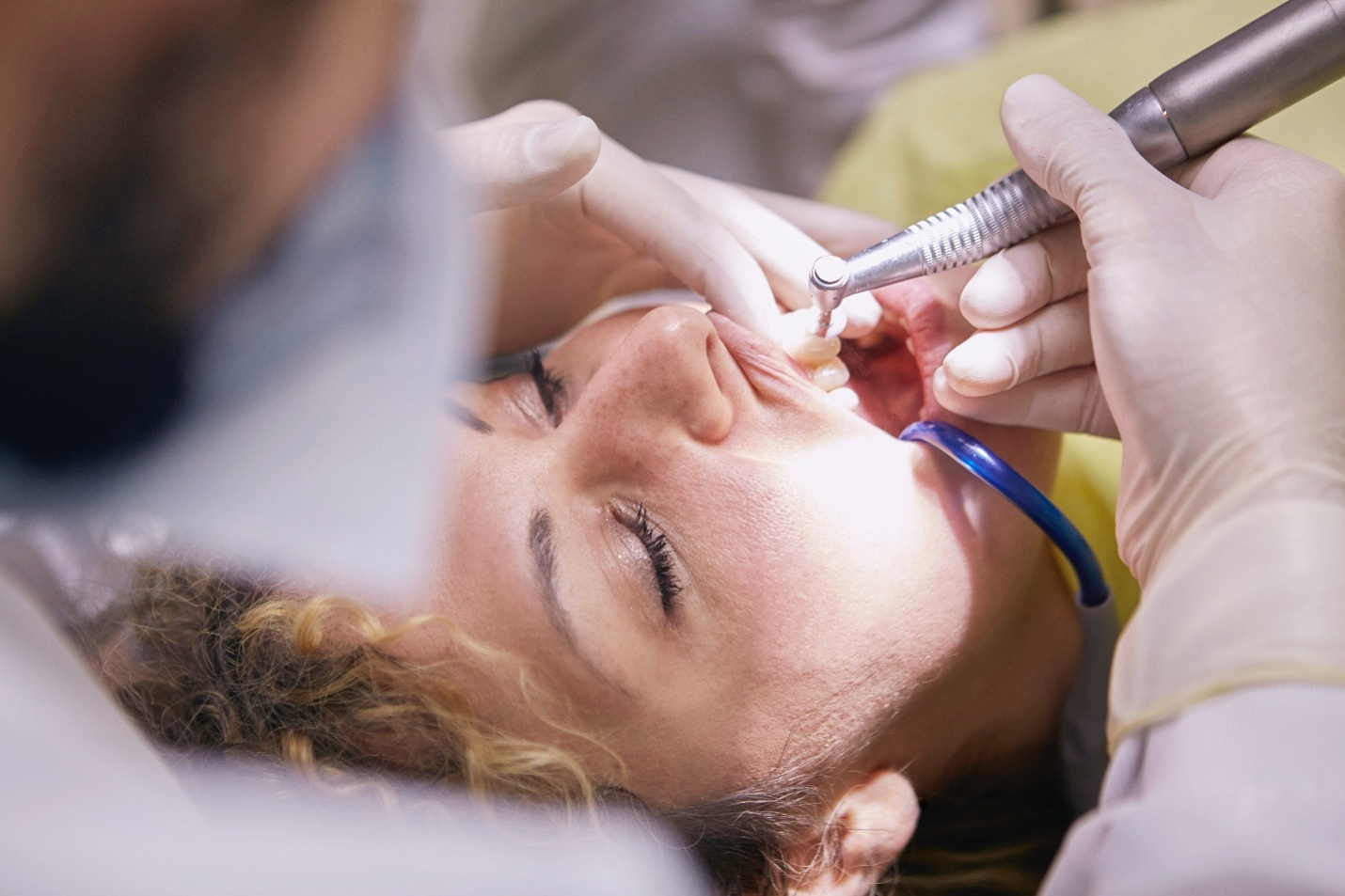 A woman getting a dental cleaning procedure done by a dentist