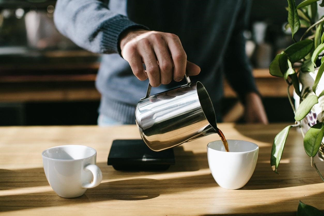 A person pouring tea into a white cup