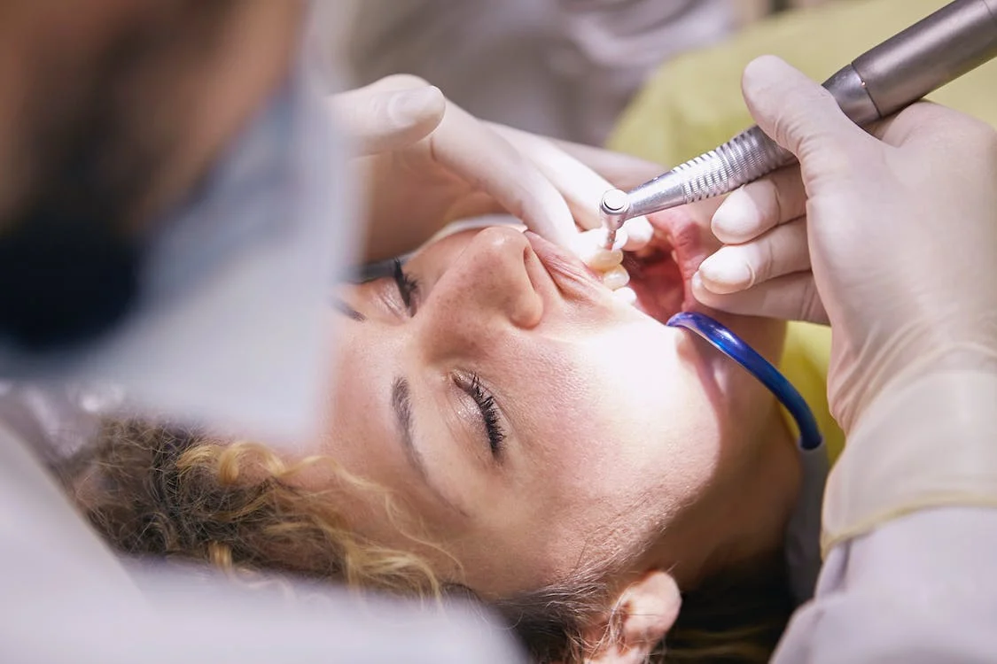 An image of a dentist performing dental cleaning for a woman