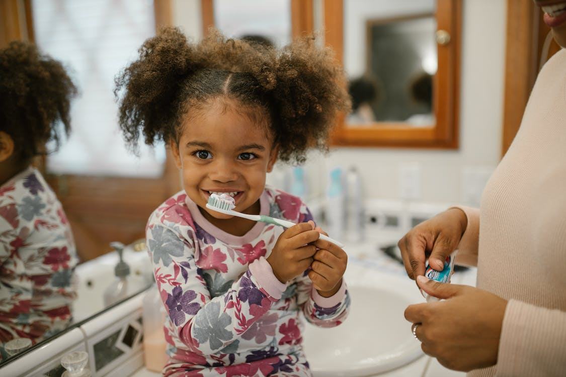 An image of a little girl brushing her teeth