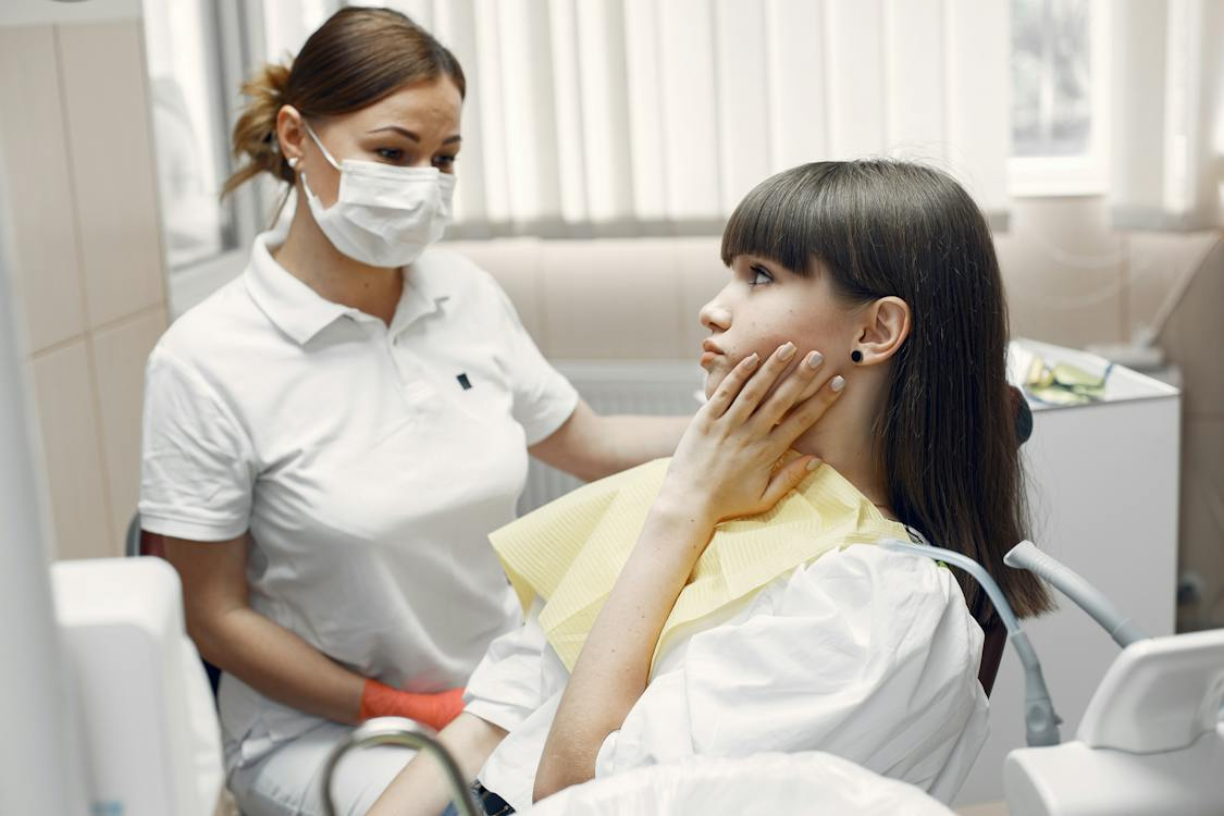 A woman at a dental clinic with a dentist holding her check due to toothache