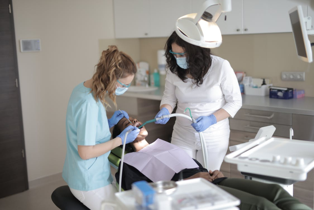 A female dentist examining the teeth of a patient with an assistant in a modern clinic before root canal therapy