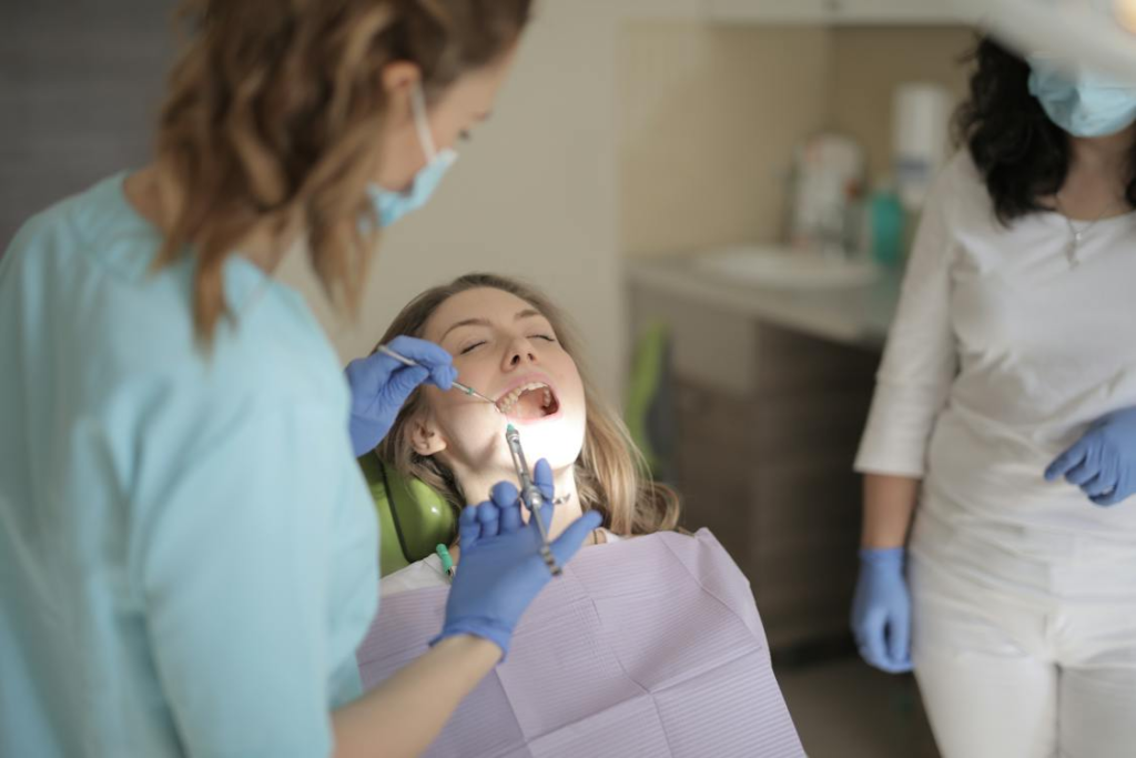 A young female dentist using injection for sedation dentistry while treating a patient in a clinic