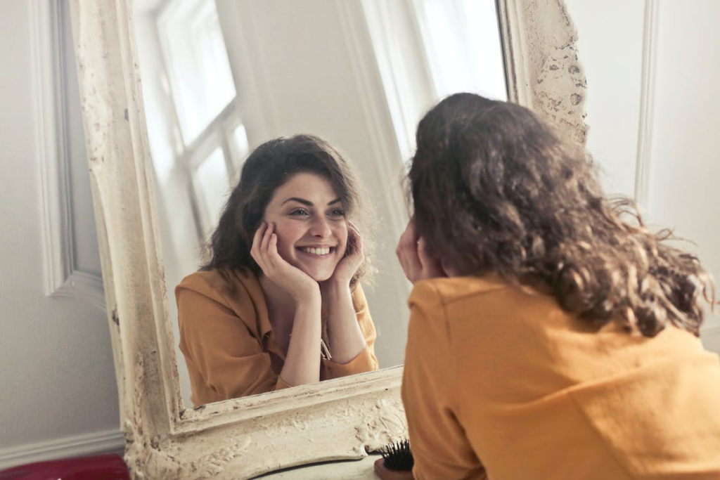 A woman looking at herself in the mirror while smiling brightly