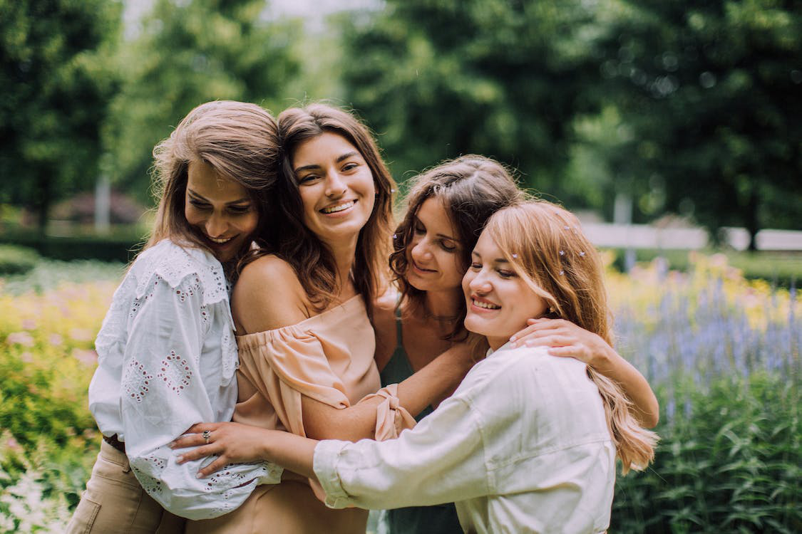 A group of four female friends hugging each other happily